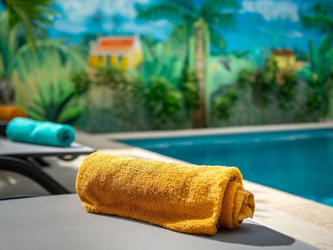 A yellow towel is rolled up on a chair next to a swimming pool.