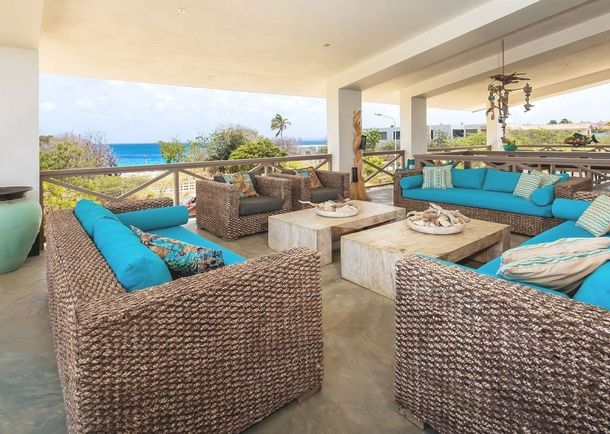 A living room with wicker furniture and a view of the ocean.