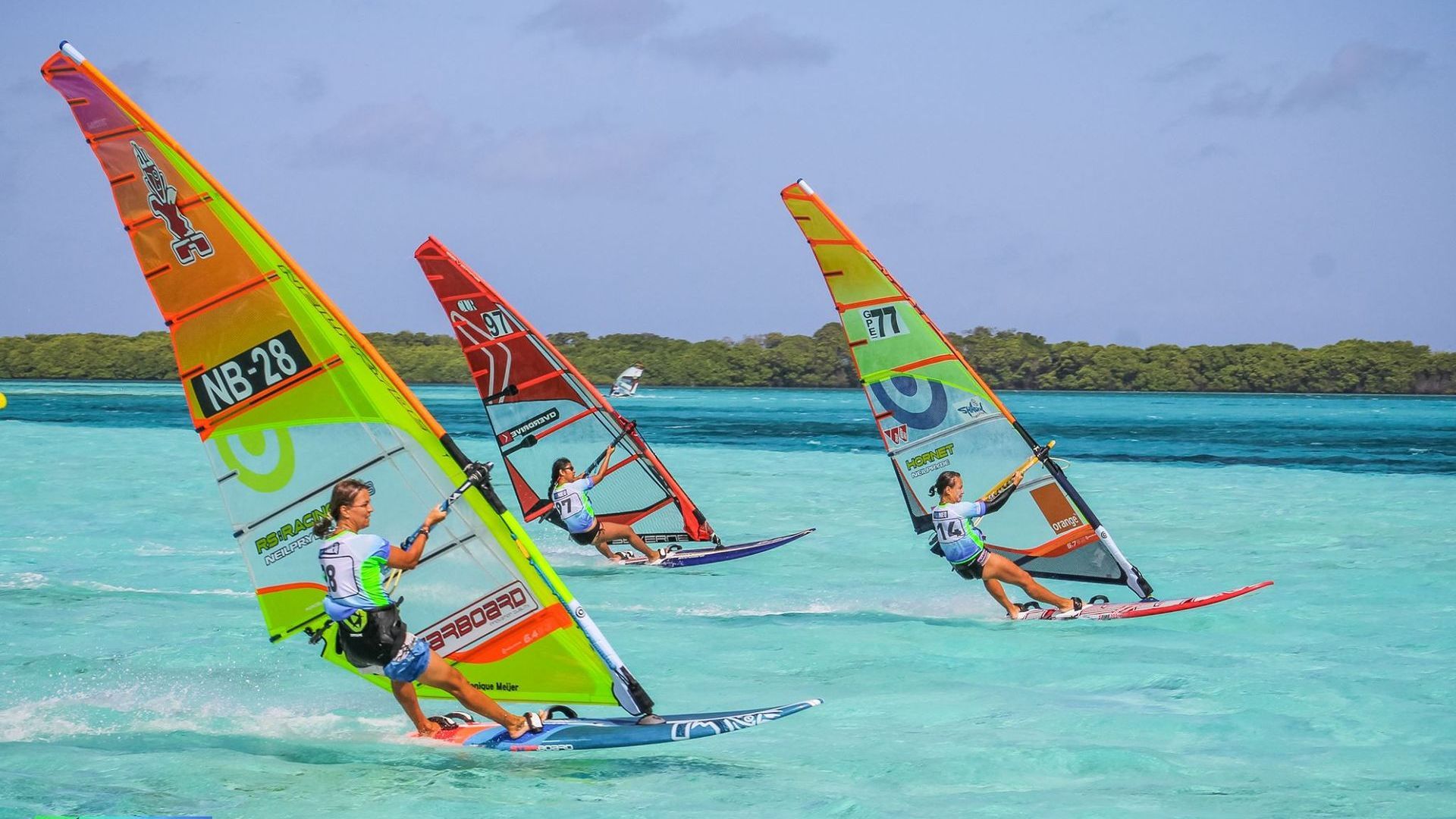 Three people are windsurfing in the ocean.