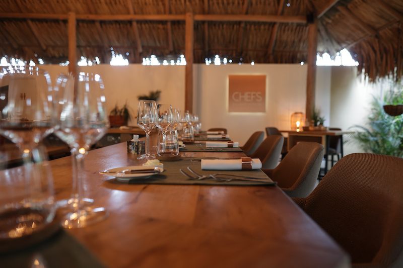 A restaurant with a wooden table and chairs and glasses of wine on it.