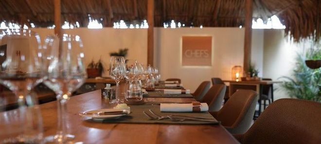 A restaurant with tables and chairs and glasses of wine on the table.