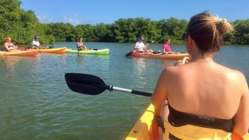 A woman is sitting in a kayak on a lake with other people in kayaks.