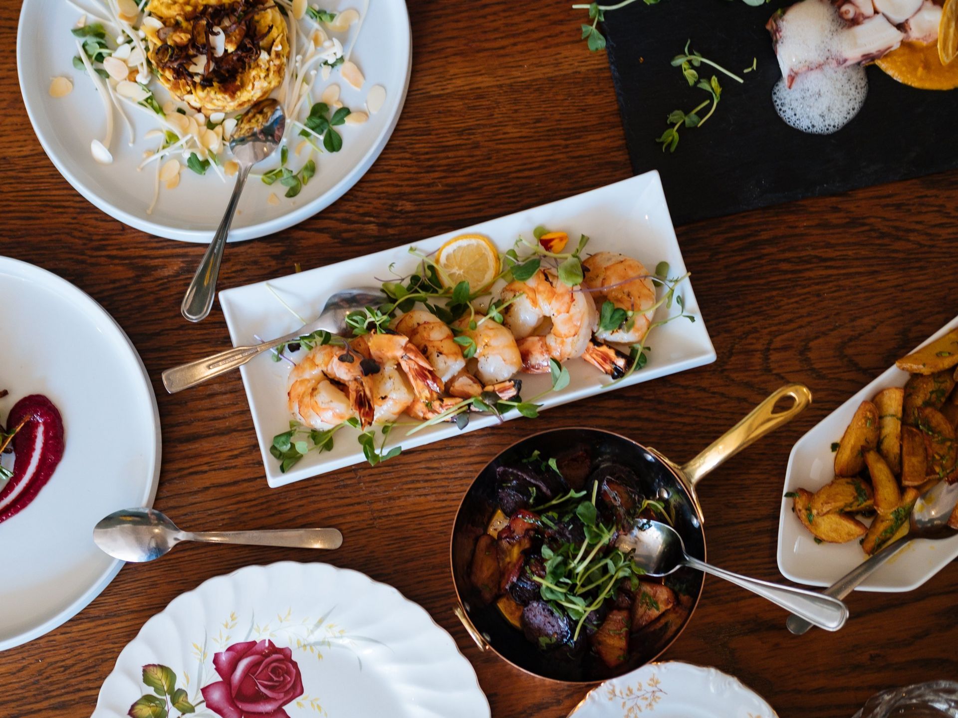 A wooden table topped with plates of food and utensils.