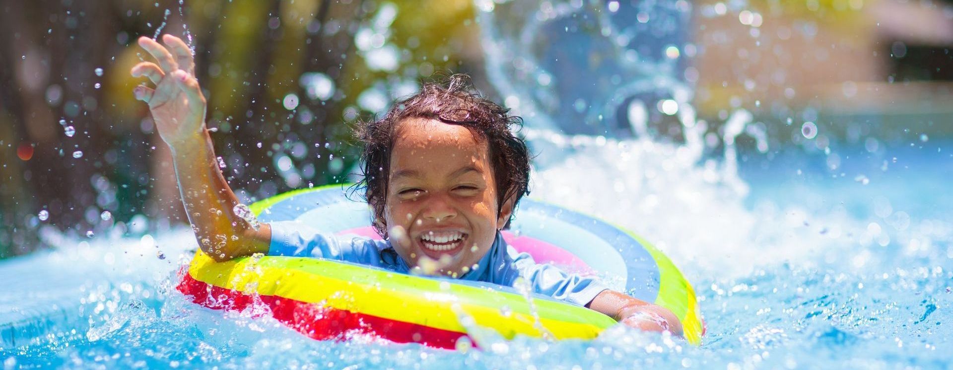 A young boy is swimming in a pool with an inflatable ring.