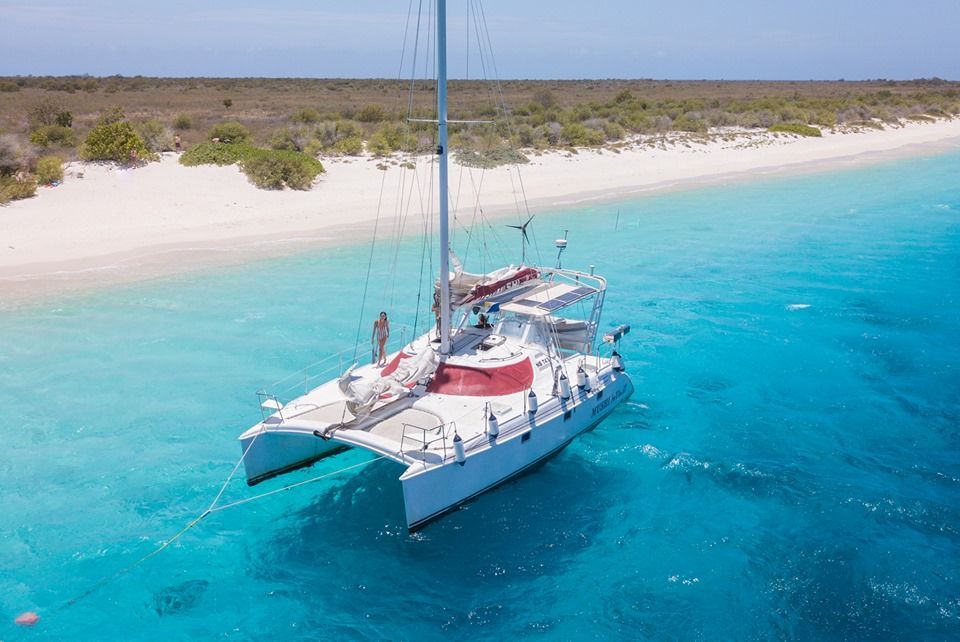 An aerial view of a sailboat in the ocean near a beach.