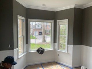 A man is painting a wall in a room while wearing a mask.