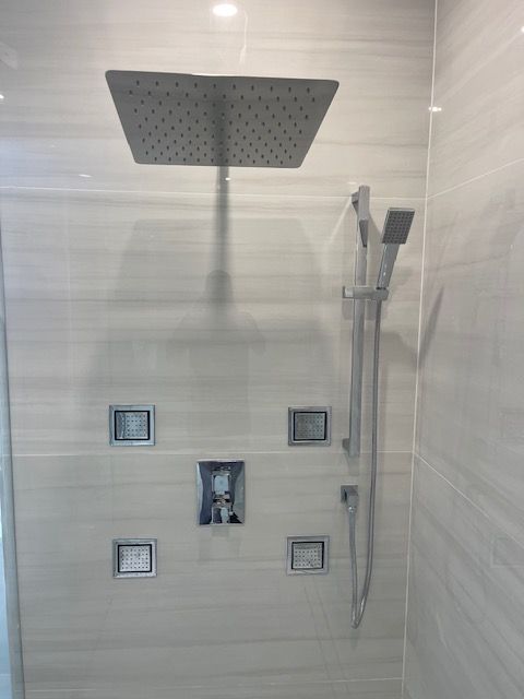 A shower head is hanging from the ceiling in a bathroom.