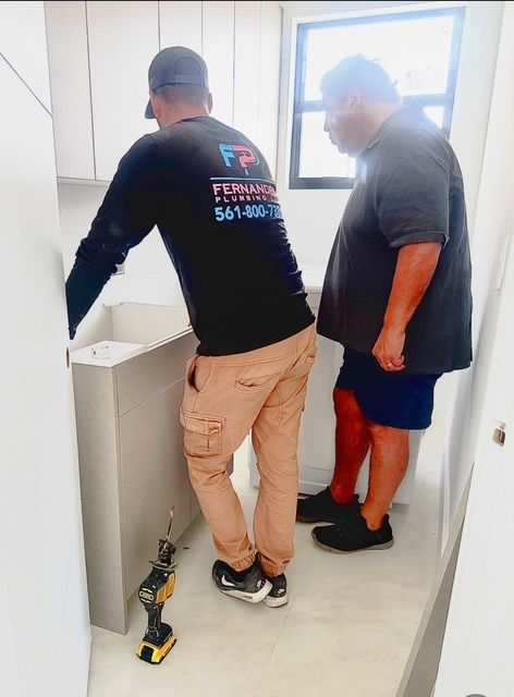 Two men are working in a kitchen and one has a shirt that says fernando