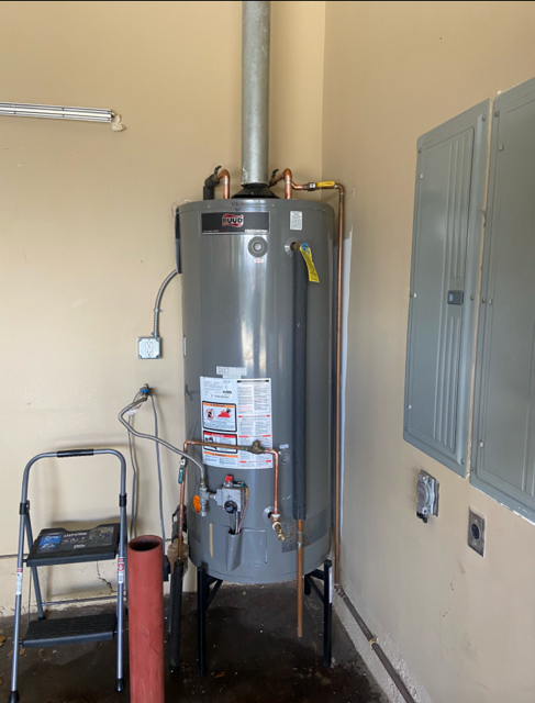 A water heater is sitting in a room next to a ladder