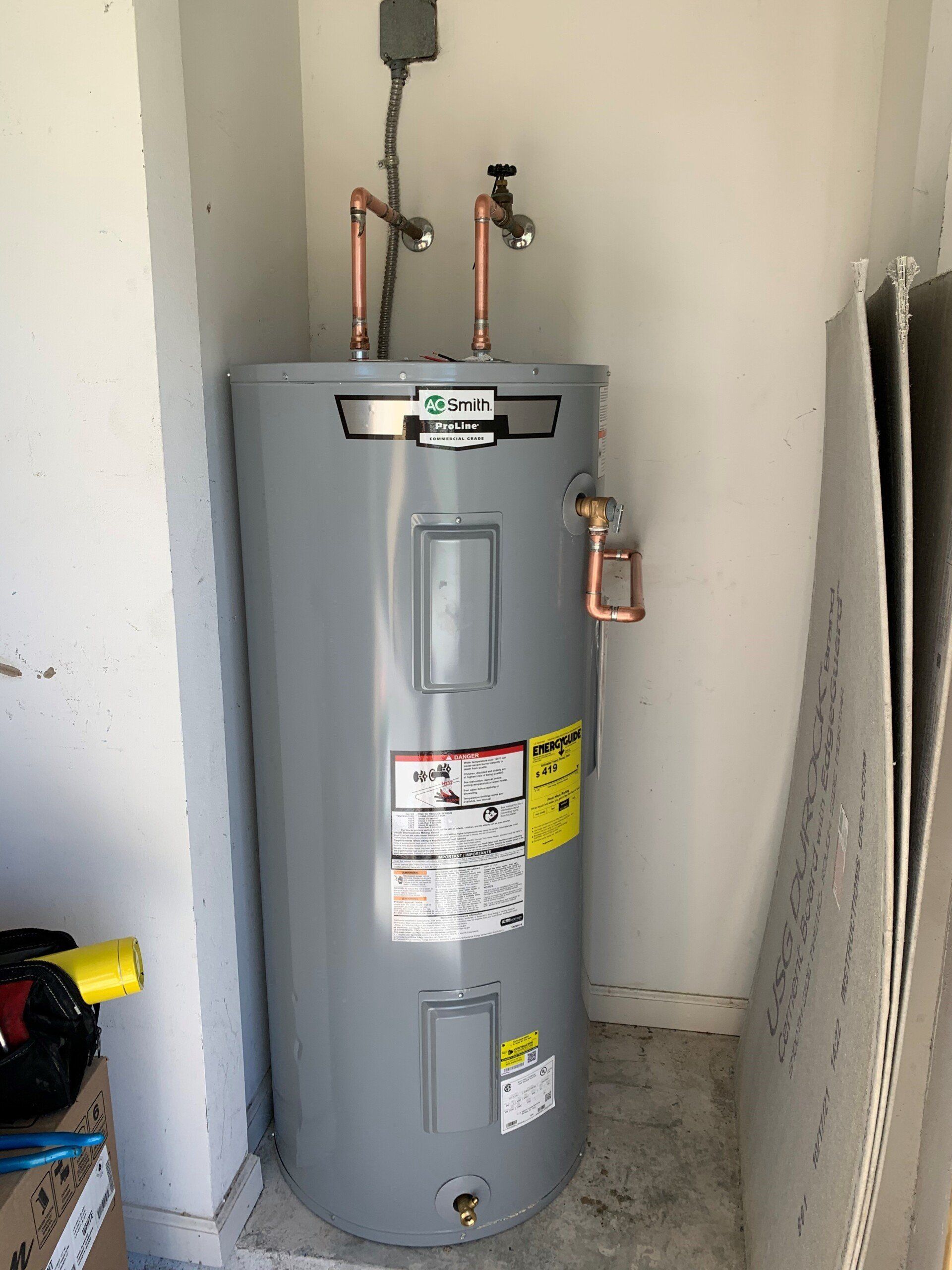 A water heater is sitting in a room next to a wall.