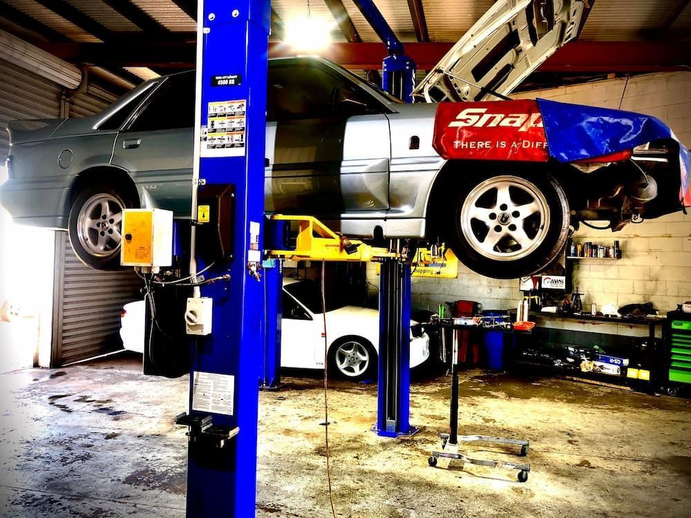 A Car Raised Up On a Lift in a Workshop — AWS Mechanical in Stuart Park, NT