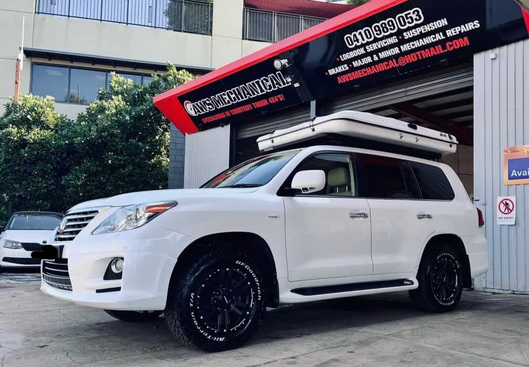A White Suv With a Tent on Top of It is Parked in Front of a Building  — AWS Mechanical in Stuart Park, NT