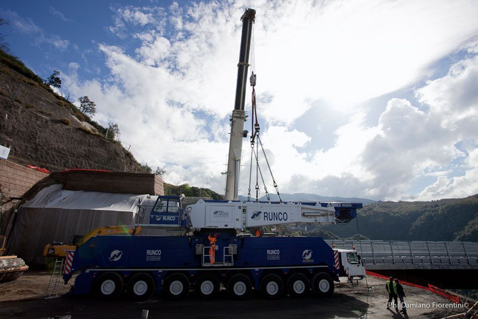 Una grande gru è posizionata sopra un camion in un cantiere edile.