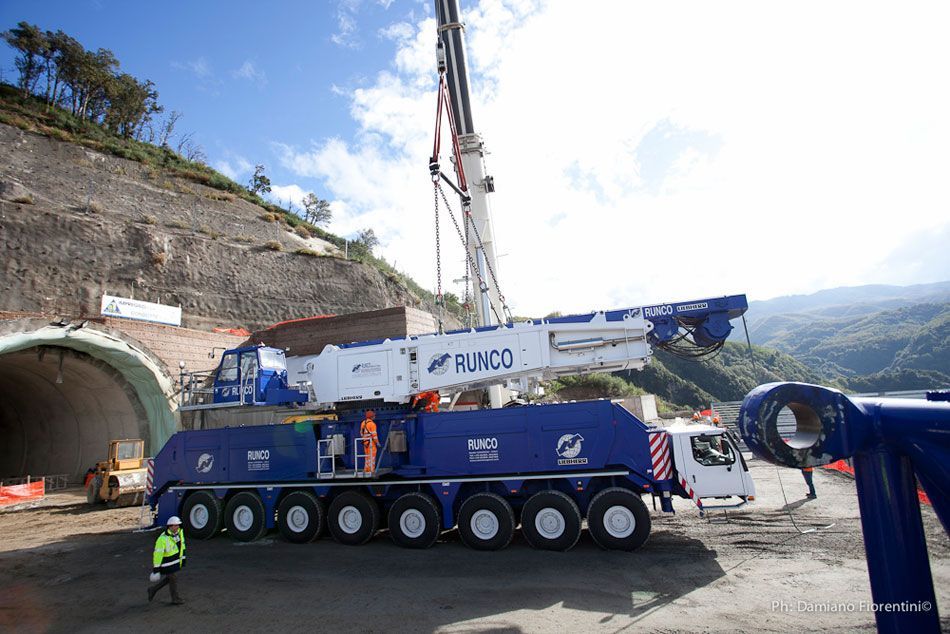 Una grande gru blu e bianca è parcheggiata davanti a un tunnel.