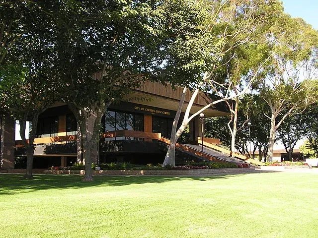 A large building is surrounded by trees and grass