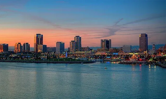 A city skyline overlooking a body of water at sunset.