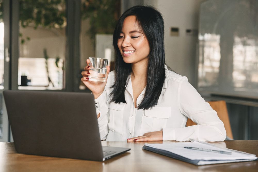 Woman Smiling While Holding a Glass of Water — Port Macquarie Pure Water In Port Macquarie, NSW