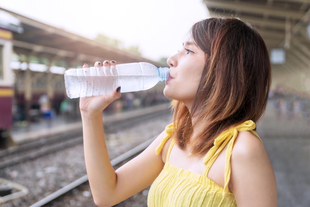 Woman in Yellow Drinking Water at a Train Station — Port Macquarie Pure Water In Wauchope, NSW