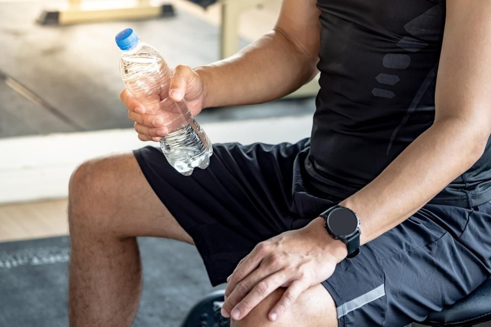 Man in Workout Clothes Holding a Water Bottle, Sitting in a Gym — Port Macquarie Pure Water In Port Macquarie, NSW