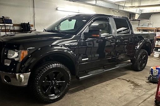 A black pickup truck is parked in a garage. A black pickup truck is parked in a garage.
