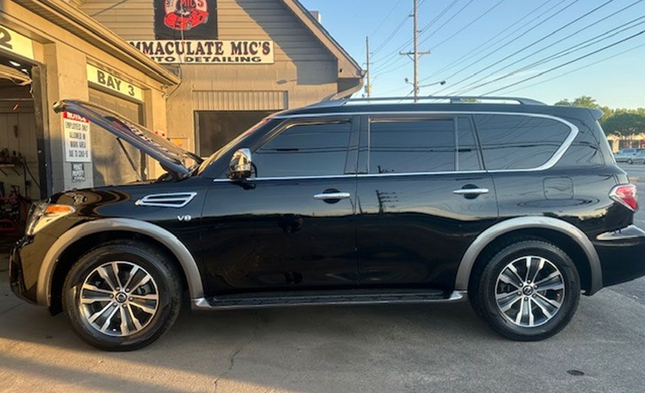 A black suv is parked in front of a garage with its hood open. A black suv is parked in front of a garage with its hood open.