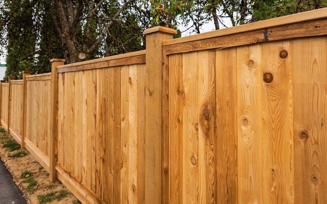 A close up of a wooden fence with trees in the background.