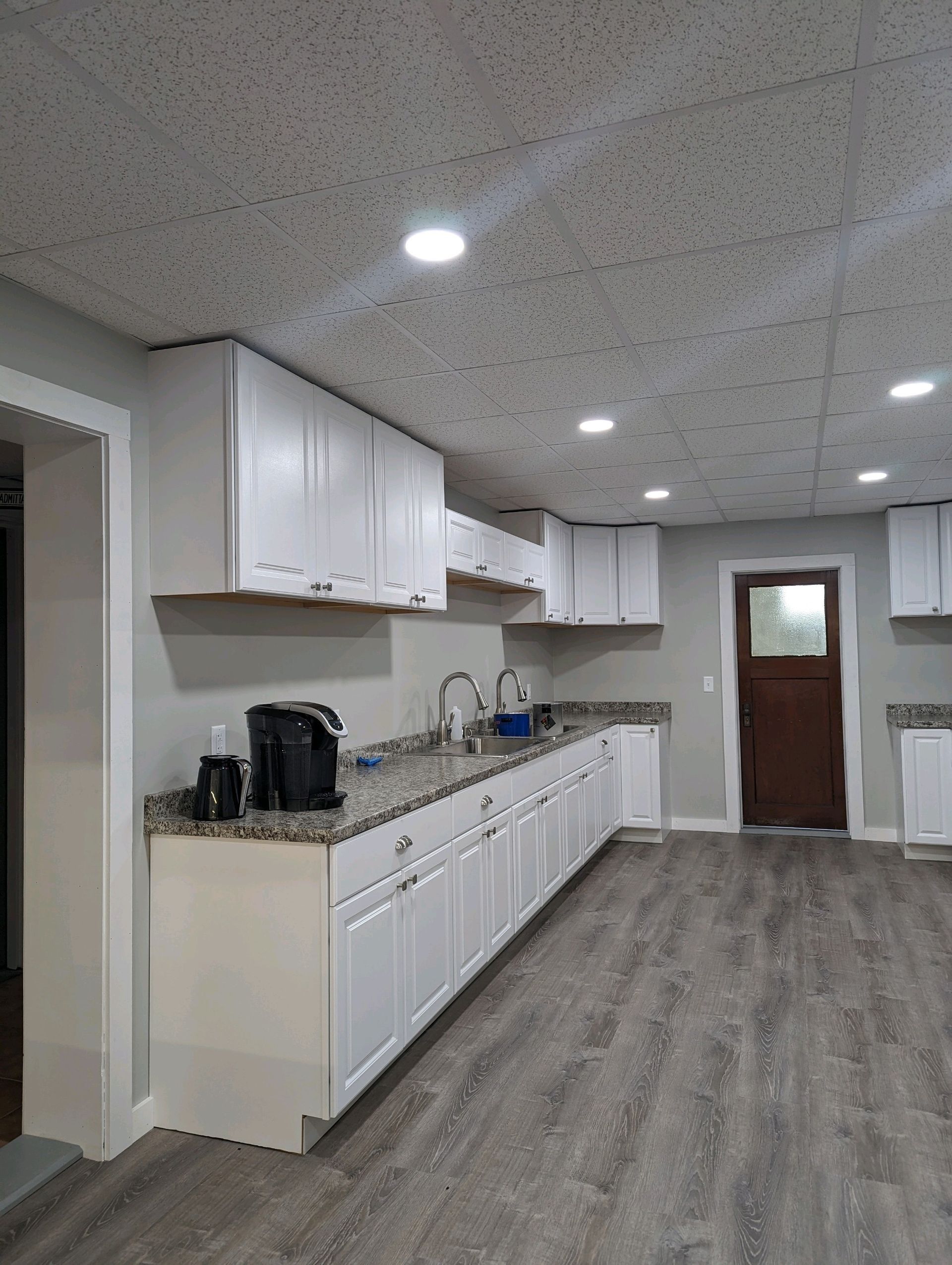 Bright kitchen with white cabinets, black appliances, and gray flooring in a modern room