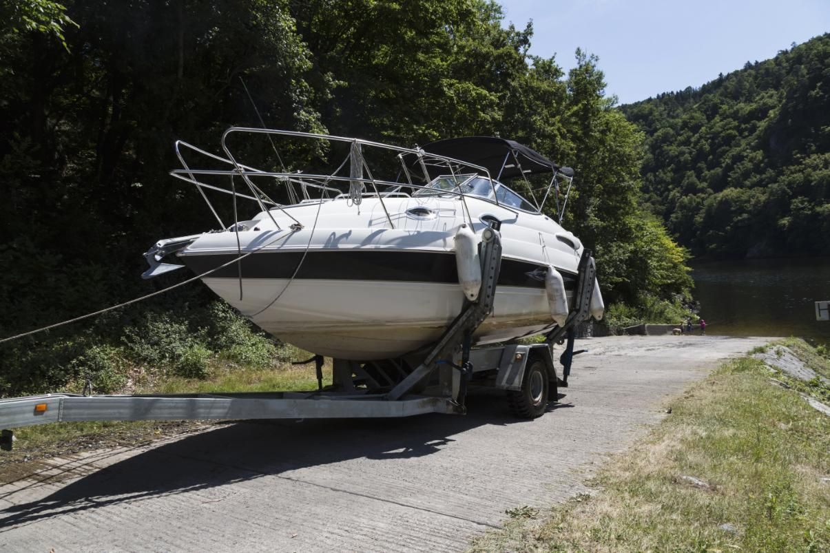 White Boat on a Trailer at a Boat Launch Ramp With Trees — Bay & Basin Storage In Nowra, NSW