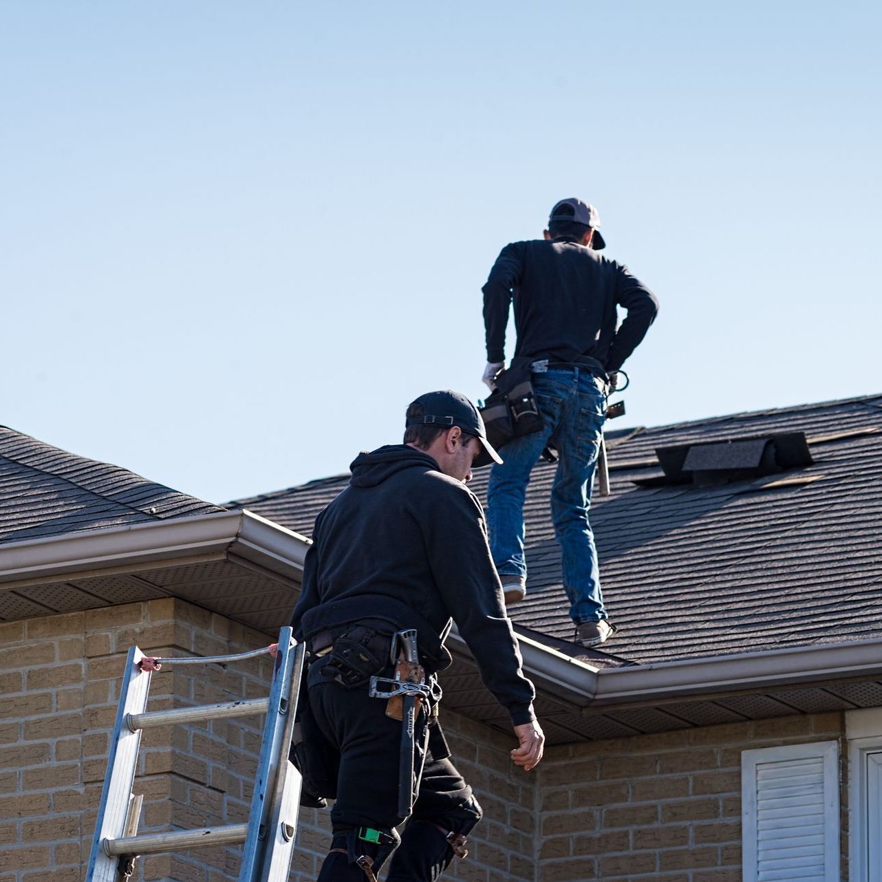 Two men are working on the roof of a house.