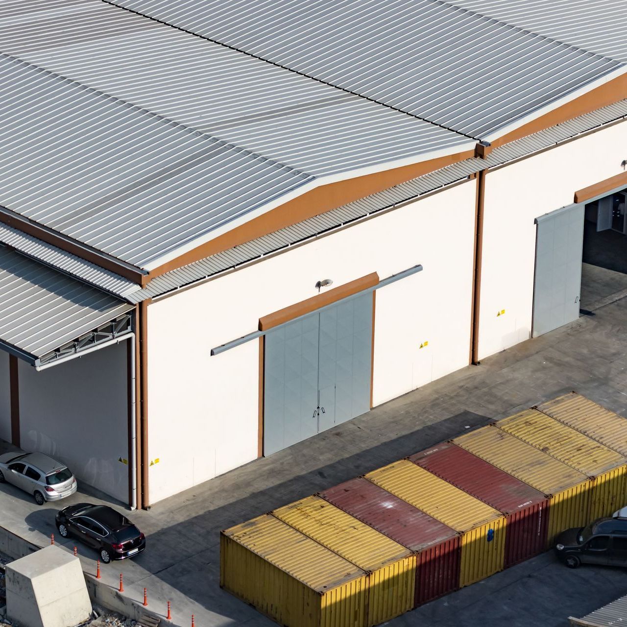 An aerial view of a warehouse with containers in front of it