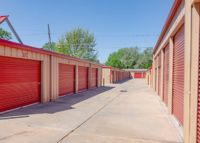Multiple numbered roll-up doors on a clean storage building under a blue sky