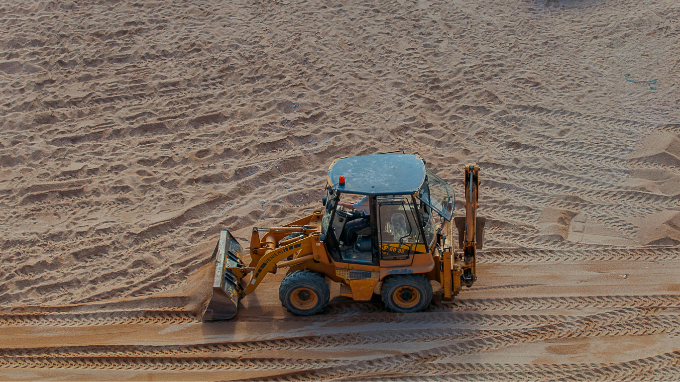 A yellow bulldozer is driving through a dirt field.