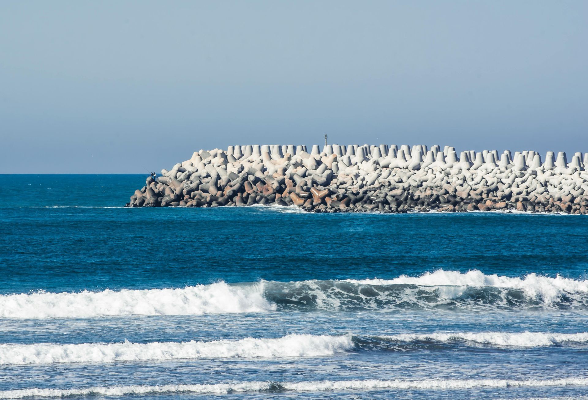 A beach with palm trees and a pier in the background