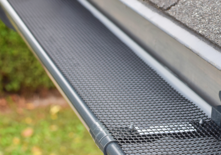 A man is installing a gutter on the roof of a house.