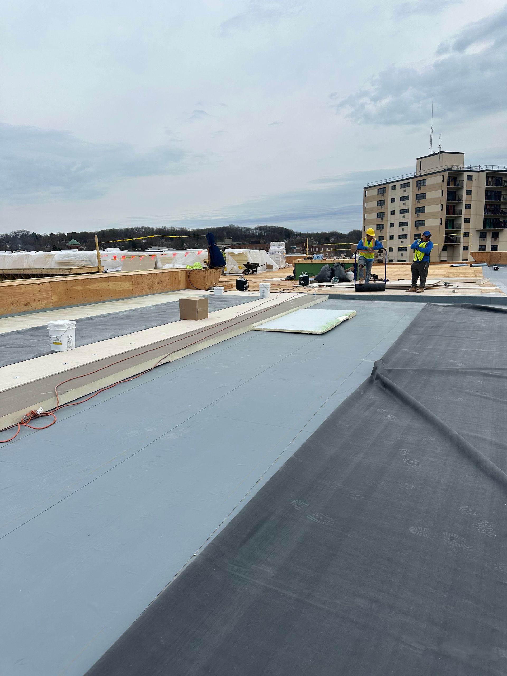 Two construction workers are working on the roof of a building.