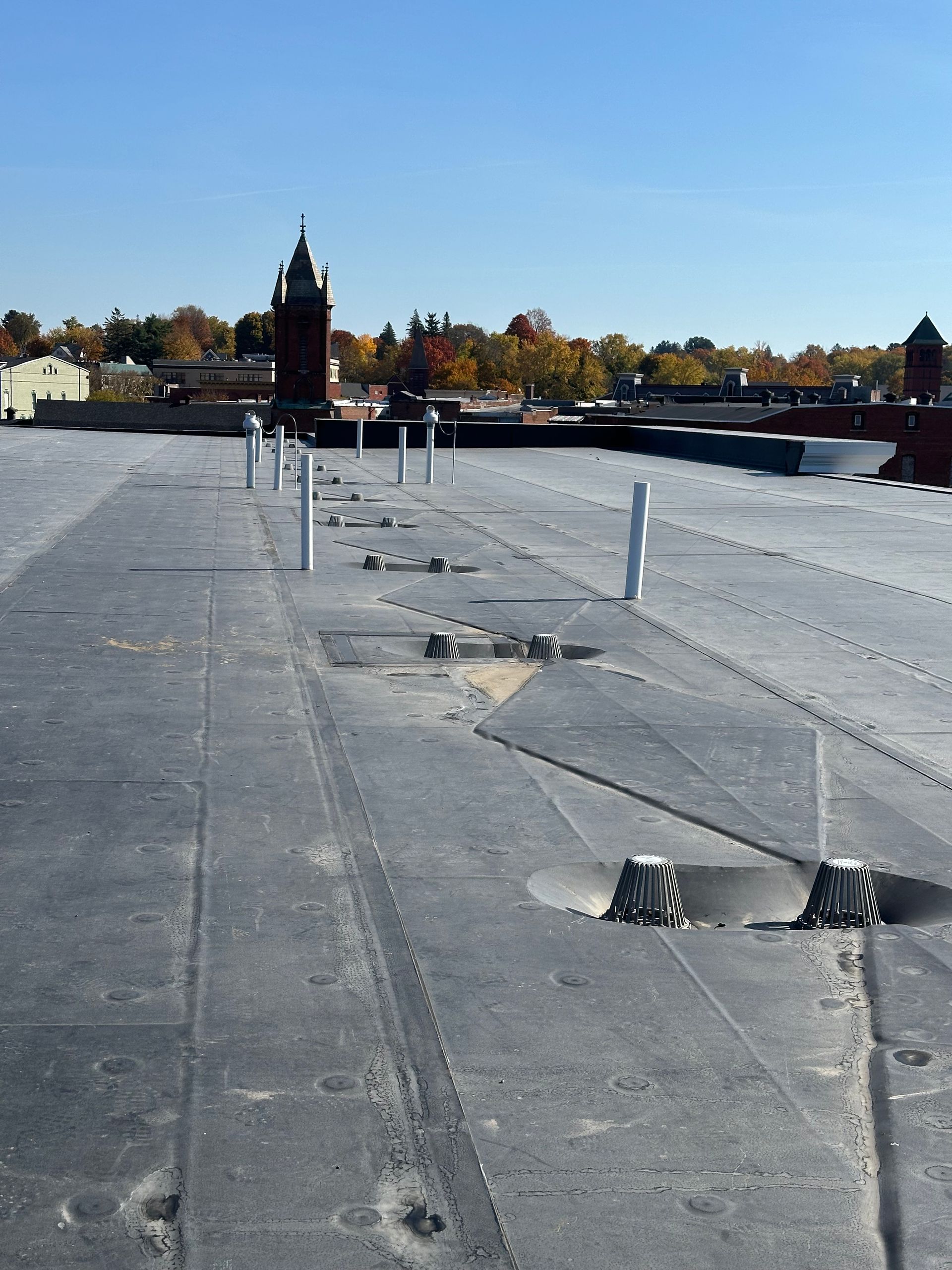 Two construction workers are working on the roof of a building.