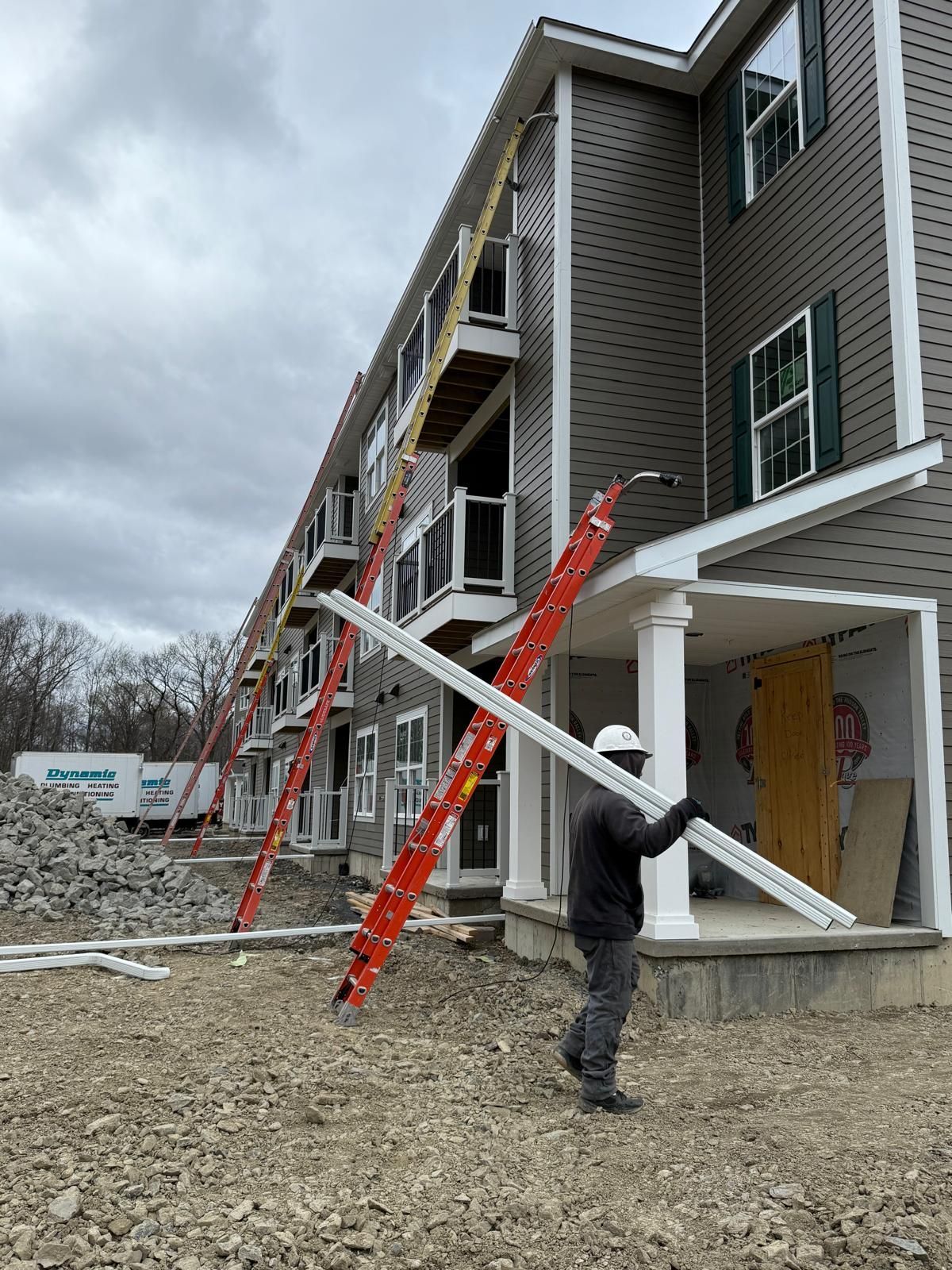 A man is installing a gutter on the side of a brick building.