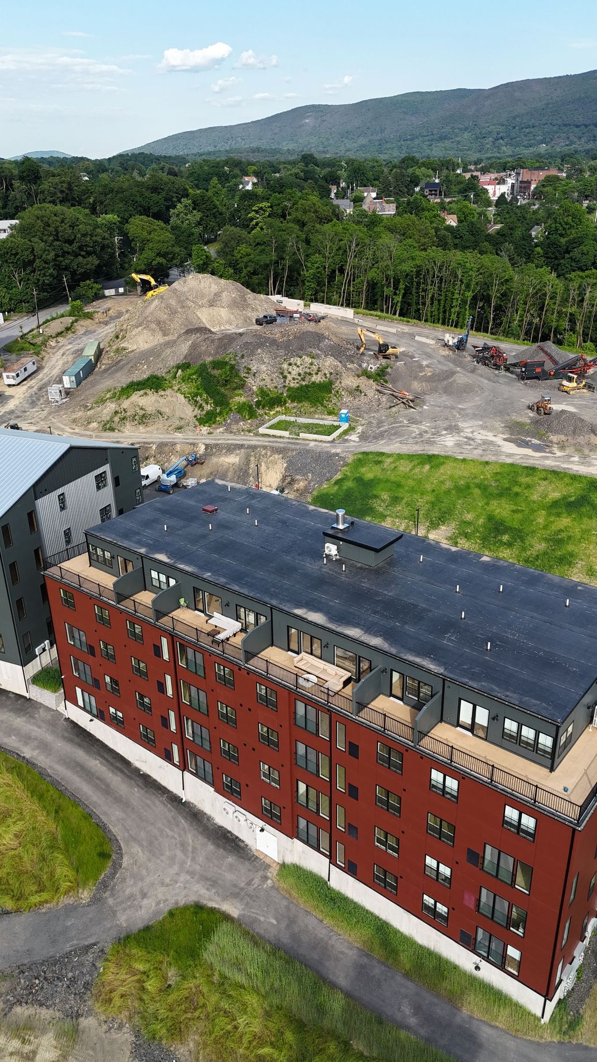 An aerial view of a large building with a black roof in the middle of a field.