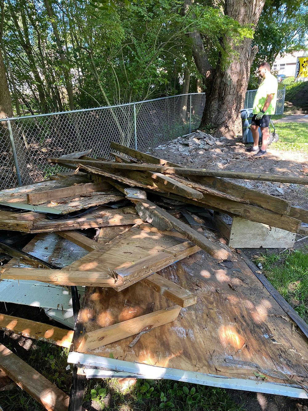 A man is standing next to a pile of wood.