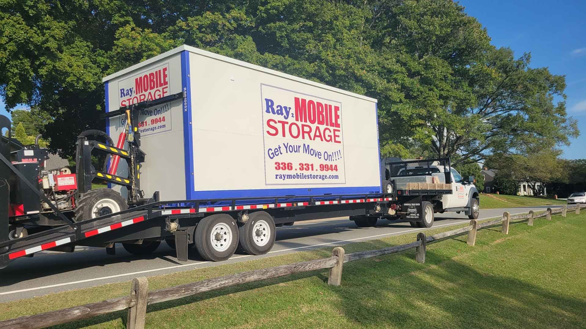 Mobile Storage Best Uses: A moving truck is driving down the road with a trailer attached to it.