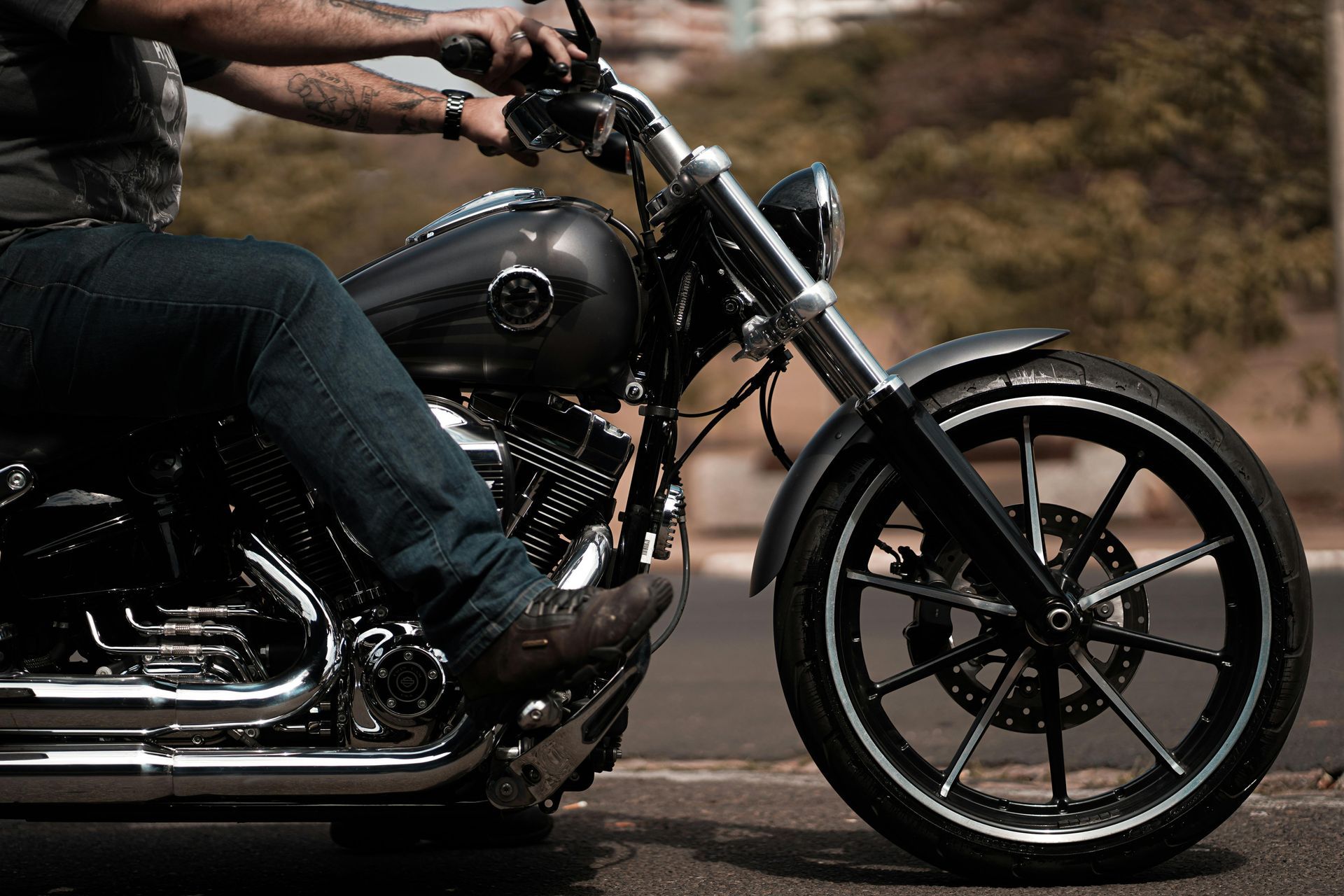 Person riding a black motorcycle on a road, close-up of the bike and wheels