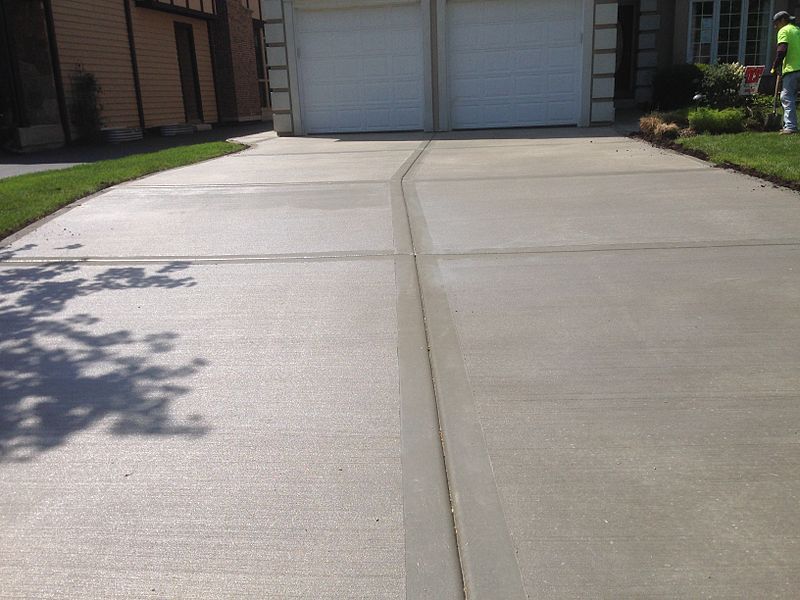 A clean, newly finished concrete driveway leading to a garage.