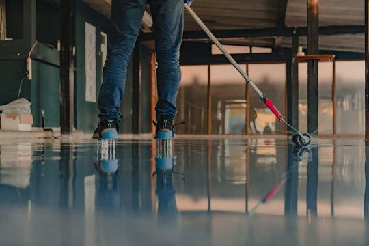 The worker applies gray epoxy resin to the new floor
