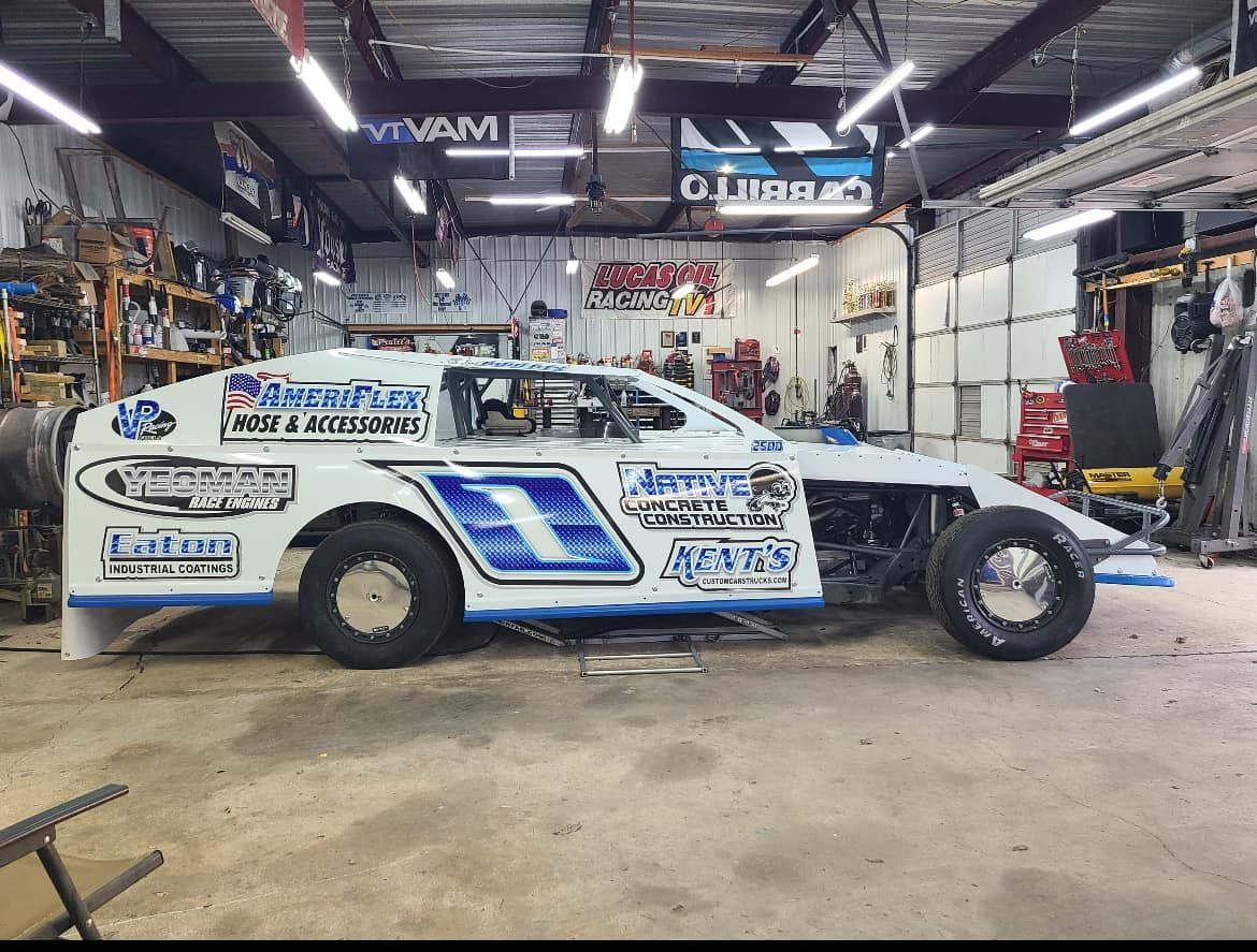 A white and blue race car is parked in a garage.