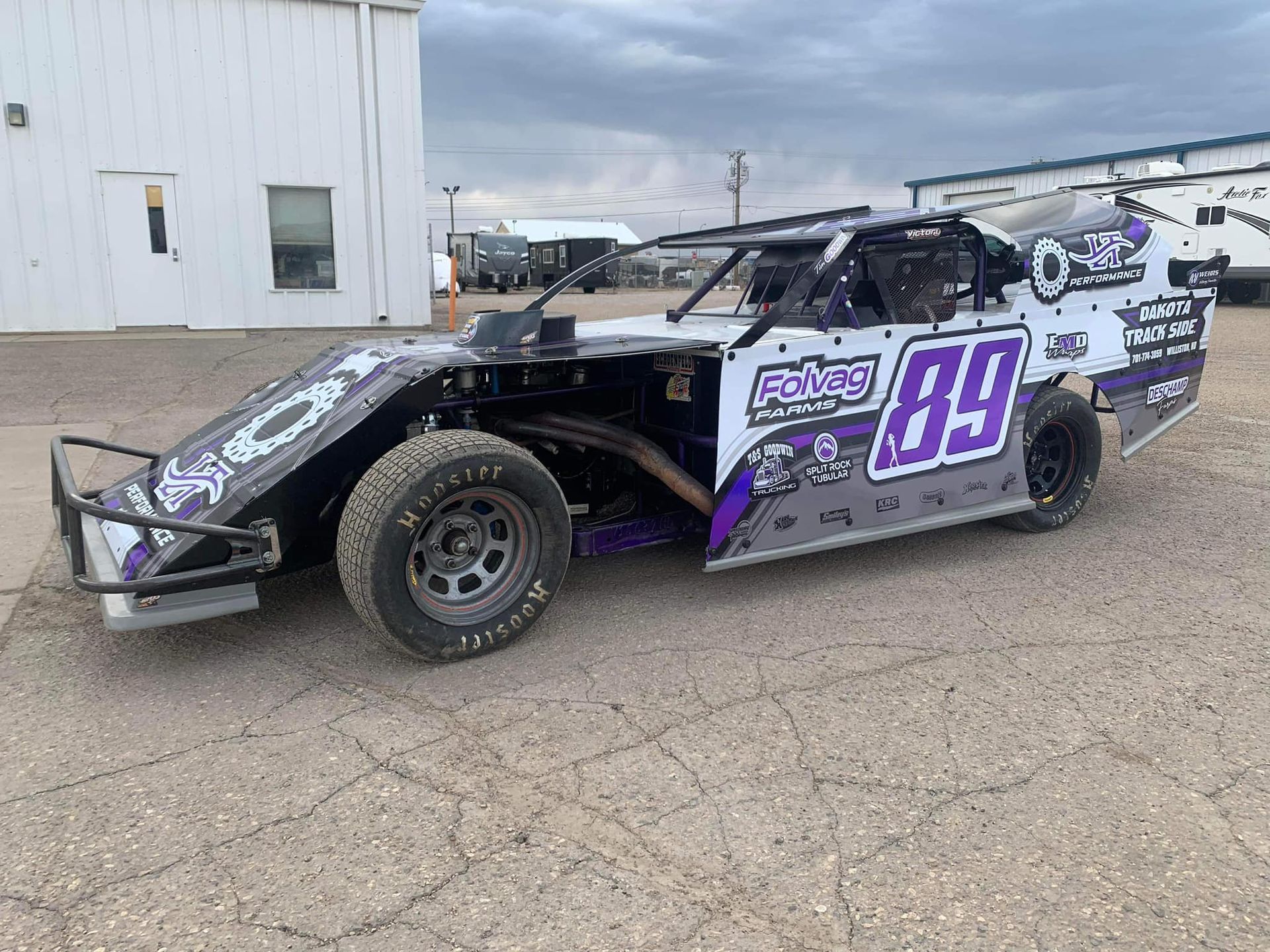 A race car is parked in a parking lot in front of a building.