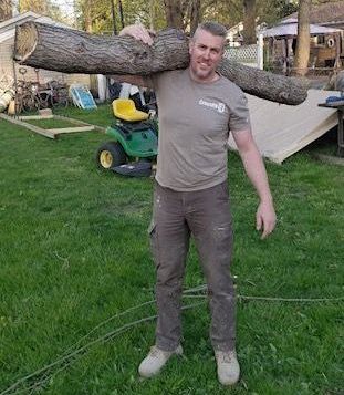 A man is carrying a large log over his shoulder.