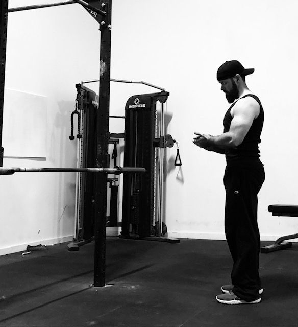 A man is standing in a gym looking at his phone
