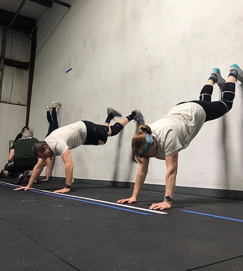 A group of people are doing handstands in a gym.