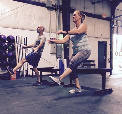 A man and a woman are doing exercises in a gym.
