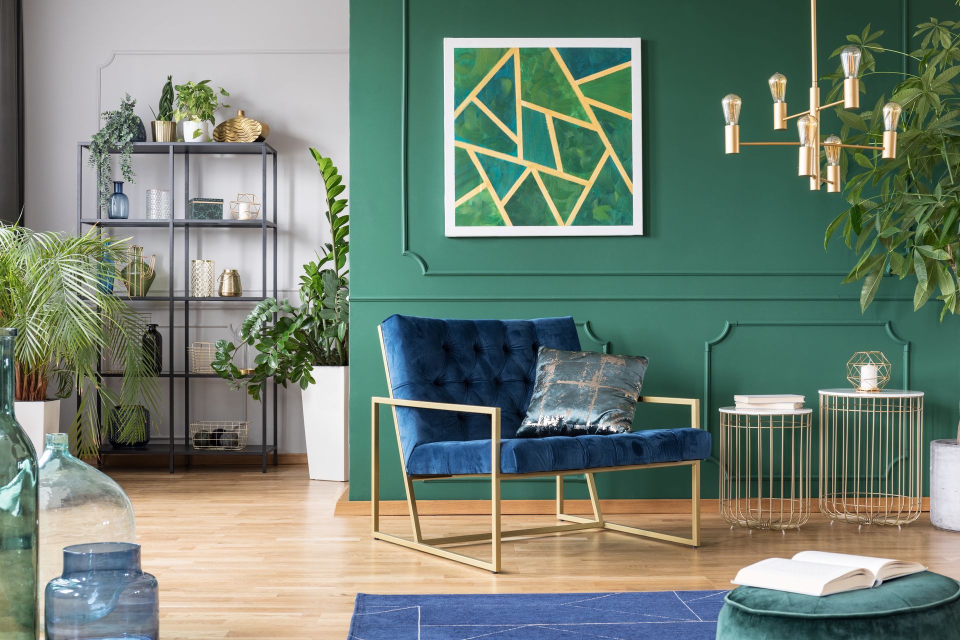 A living room with green walls , a blue chair and a painting on the wall. color psychology